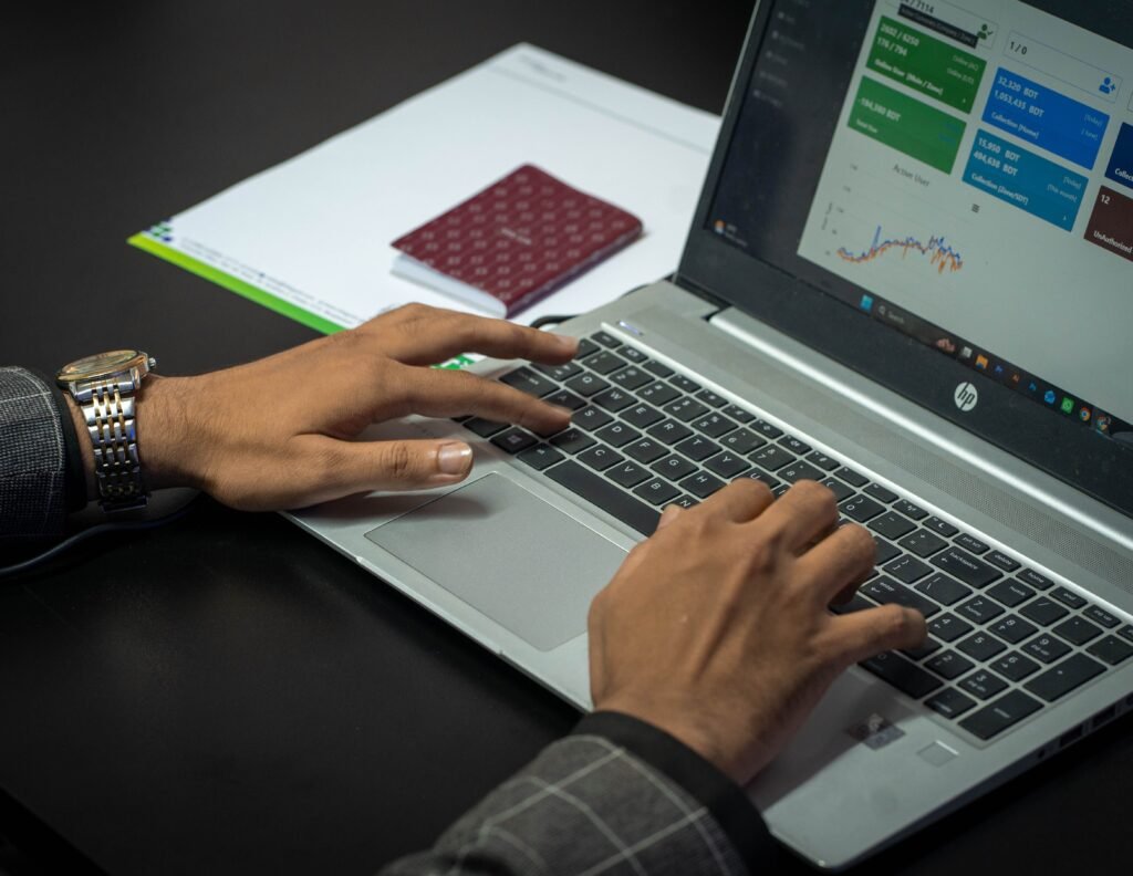 Close-up of hands on a laptop keyboard with a business dashboard on screen, ideal for finance or tech themes.